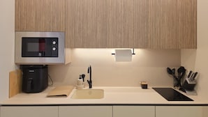 Una cocina moderna con microondas integrado, cafetera, lavamanos y estufa.