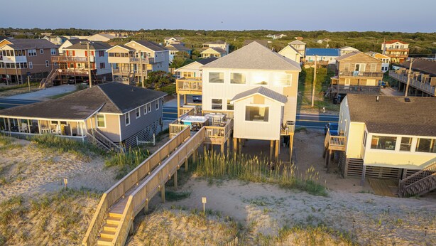 A coastal residential area with houses on stilts, a wooden boardwalk, and a sandy beach. - Spacious 5-bedroom house in charming Kitty Hawk with AC (Kitty Hawk)