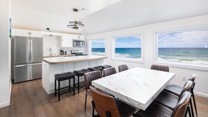 A modern kitchen with a large island, stainless steel appliances, and a view of the ocean. - Spacious 5-bedroom house in charming Kitty Hawk with AC (Kitty Hawk)