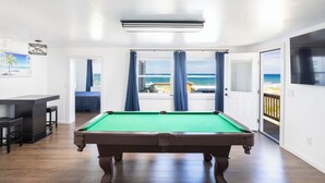 A pool table in a room with a view of the ocean through large windows. - Spacious 5-bedroom house in charming Kitty Hawk with AC (Kitty Hawk)