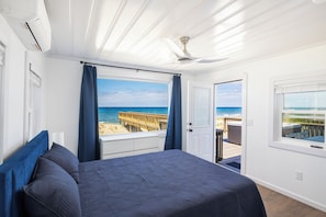 Ein Schlafzimmer mit Bett, Deckenventilator und Blick auf den Strand.