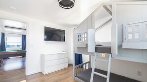 A bunk bed room with a television, a window with curtains, and a pool table. - Spacious 5-bedroom house in charming Kitty Hawk with AC (Kitty Hawk)
