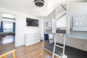 Ein Schlafraum mit Etagenbetten, einem Fernseher, einem Fenster mit Vorhängen und einem Billardtisch.