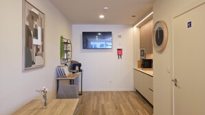Una cocina moderna con microondas integrado, cafetera y un pequeño comedor con mesa y sillas.
