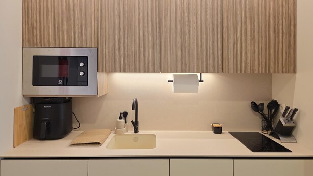 Una cocina moderna con microondas integrado, cafetera, lavamanos y estufa.