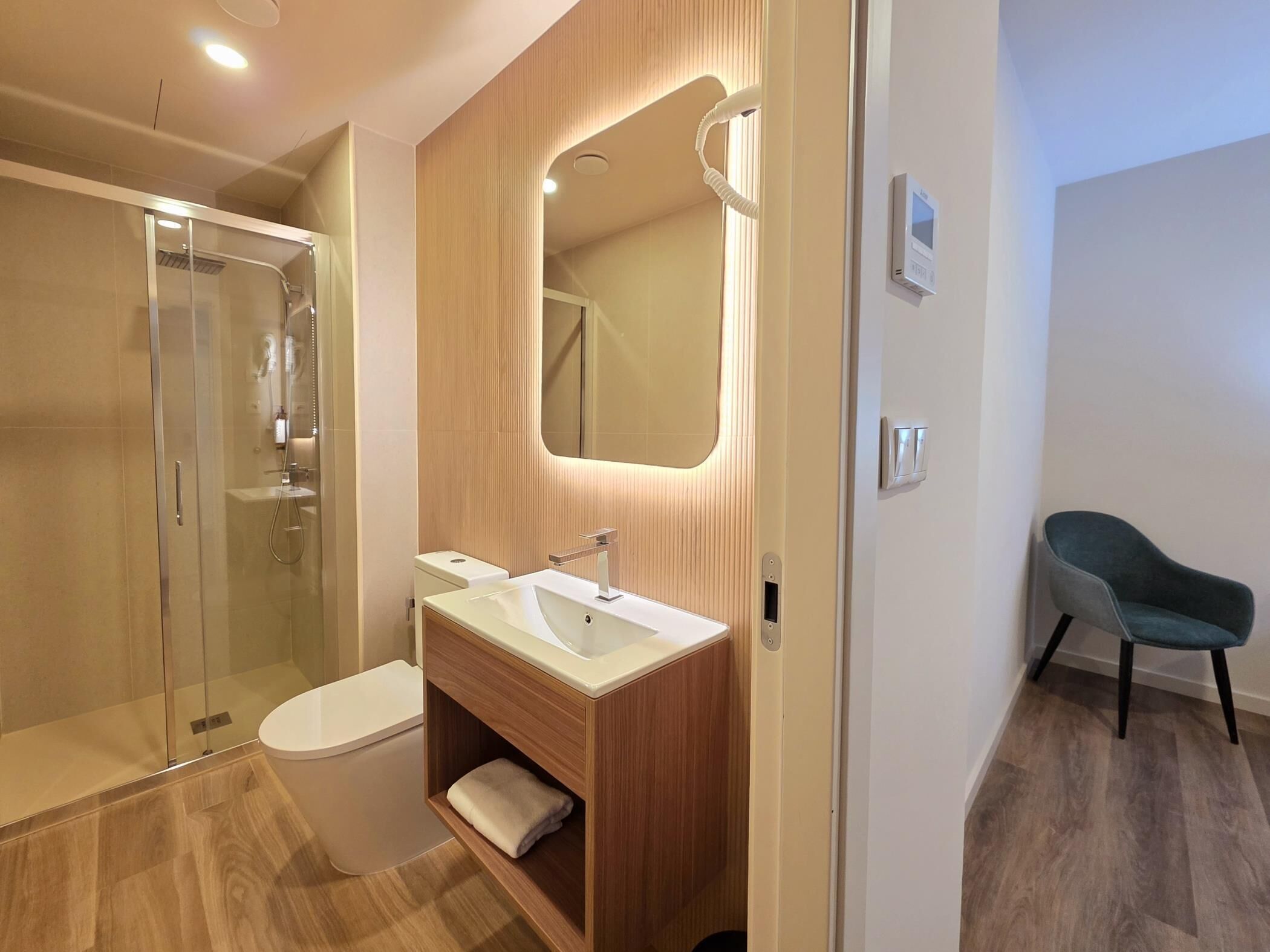 Ein modernes Badezimmer mit Duschkabine aus Glas, Waschtisch mit Spiegel und separatem WC.