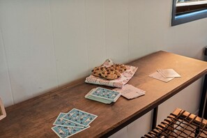 Ein Holztisch mit einem Kartenstapel, ein paar Karten auf dem Boden und einer Tischdecke mit Muster.