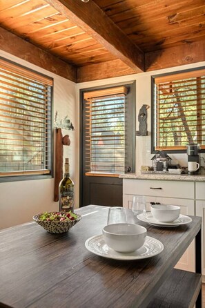 A wooden dining table with a bottle, bowls, and a basket of salad. - Solheim Lodge| Hot Tub, Fire Pit, EV Charger, Pets (Big Bear Lake)