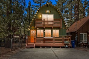 Une cabane en bois avec une véranda, une petite terrasse et un espace clôturé.