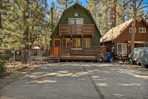 A cabin with a wooden deck, a front porch, and a small attached structure. - Solheim Lodge| Hot Tub, Fire Pit, EV Charger, Pets (Big Bear Lake)