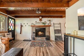Ein gemütliches Blockhaushaus-Interieur mit Kamin, Holzboden, einer Bank und einer Leiter.