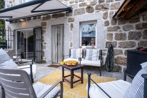 A stone building with a patio area featuring outdoor seating and a table with baskets. - Oya Vacation Rental - CHAUDEYRAC - Vacation Rental (CHAUDEYRAC)
