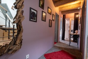 A hallway with a red carpet, wooden beams, and framed pictures on the wall. - Oya Vacation Rental - CHAUDEYRAC - Vacation Rental (CHAUDEYRAC)