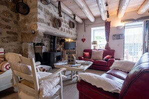 A cozy living room with a fireplace, leather sofas, and a television. - Oya Vacation Rental - CHAUDEYRAC - Vacation Rental (CHAUDEYRAC)