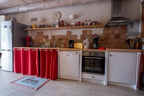 A compact kitchen with a dishwasher, oven, and a coffee maker on the countertop. - Oya Vacation Rental - CHAUDEYRAC - Vacation Rental (CHAUDEYRAC)