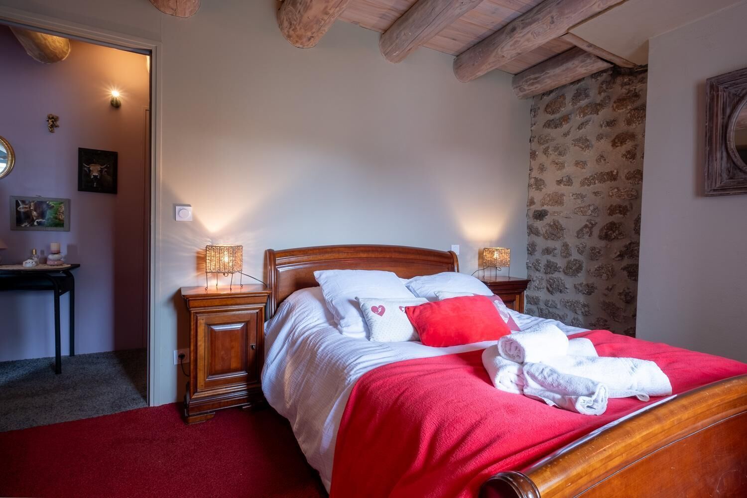 A bedroom with a wooden bed, two bedside tables with lamps, a red carpet, and a patterned wall.