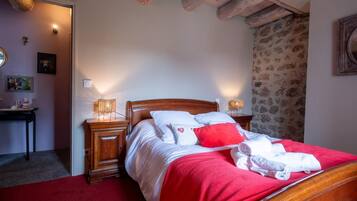 A bedroom with a wooden bed, two bedside tables with lamps, a red carpet, and a patterned wall.