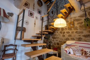 A rustic interior with a staircase, wooden furniture, and a bed with patterned bedding. - Oya Vacation Rental - CHAUDEYRAC - Vacation Rental (CHAUDEYRAC)