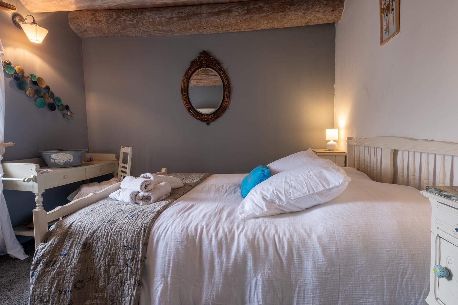 Quarto com cama, mesa de cabeceira e espelho na parede.