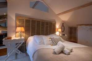 A bedroom with a bed, bedside lamps, a wooden headboard, a small desk, and a hanging coat rack. - Oya Vacation Rental - CHAUDEYRAC - Vacation Rental (CHAUDEYRAC)