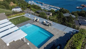 Une piscine avec des chaises longues, un court de tennis et un port de plaisance avec des bateaux.