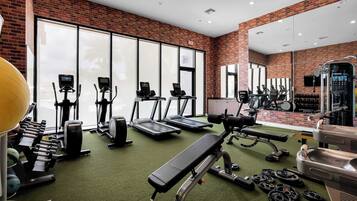 A gym with treadmills, elliptical machines, free weights, and a bench press.