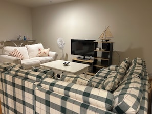 Ein Wohnzimmer mit einer Couch, einem Couchtisch, einem Fernseher und einem Ventilator.