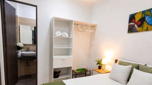 A hotel room with a bed, a wardrobe, a bedside table with a lamp, a small plant, and a bathroom visible through an open door. - Private villa with an infinity pool and a sports court · 20 guests (Antioquia)