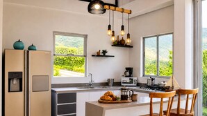 A modern kitchen with a built-in refrigerator, a coffee maker, and a view of greenery. - Private villa with an infinity pool and a sports court · 20 guests (Antioquia)