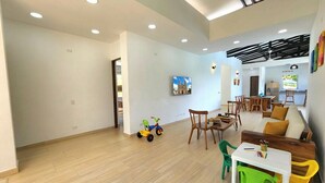 A spacious room with a dining area, a sofa, and a play area with toys. - Private villa with an infinity pool and a sports court · 20 guests (Antioquia)