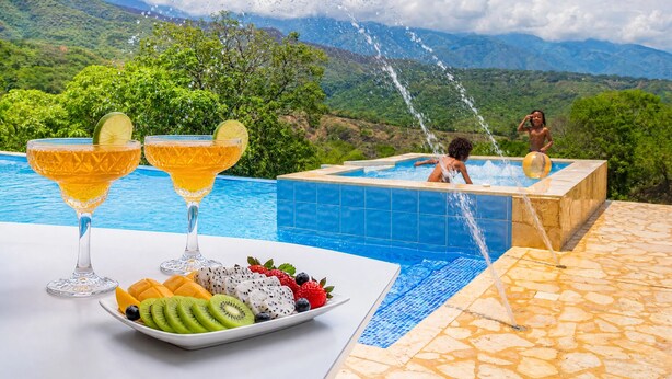 A pool with a tropical view, a fruit platter, and two drinks. - Private villa with an infinity pool and a sports court · 20 guests (Antioquia)