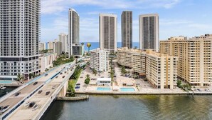 A high-rise hotel with multiple floors, a swimming pool, and a view of the water body. - Spacious Clermont Villa Sleeps 16 Pool (Hallandale Beach)