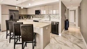 A modern kitchen with a central island, bar stools, stainless steel appliances, and a tiled backsplash. - Spacious Clermont Villa Sleeps 16 Pool (Hallandale Beach)