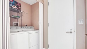 A laundry room with two washers and dryers, a shelf with detergent, and a closed door. - Spacious Clermont Villa Sleeps 16 Pool (Hallandale Beach)