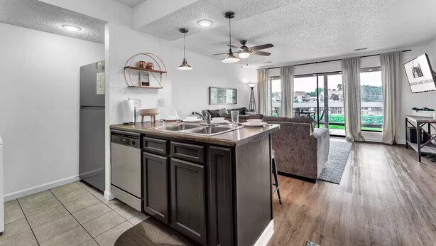 A modern kitchen with a central island, built-in appliances, and a dining area with a view. - Golf View, 2 porches, 3 pools, Hot Tub, Resort! (Branson)