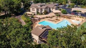 A large house with a swimming pool, surrounded by trees and a hilly landscape. - Golf View, 2 porches, 3 pools, Hot Tub, Resort! (Branson)