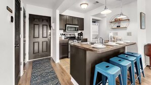 A modern kitchen with dark cabinetry, a central island with stools, and a microwave above the stove. - Golf View, 2 porches, 3 pools, Hot Tub, Resort! (Branson)