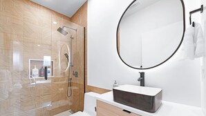 A modern bathroom with a glass shower enclosure, a white toilet, a rectangular sink with a dark basin, and a large mirror with a black frame. - Modern 3BR Gem | Close to Transit | 15m to DT (Vancouver)