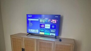 Un televisor sobre un mueble de madera con una pantalla digital que muestra varios servicios de transmisión.