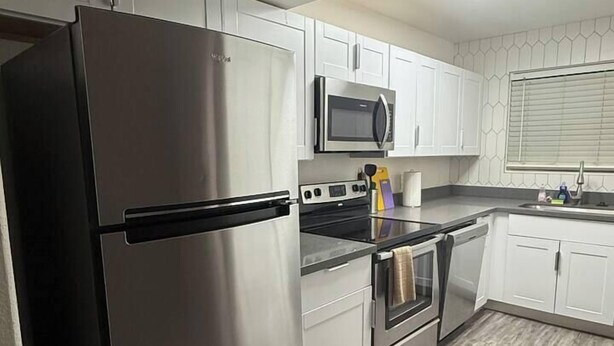 Una cocina moderna con electrodomésticos de acero inoxidable, armarios blancos y un salpicadero con diseño.