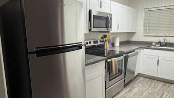 A modern kitchen with stainless steel appliances, white cabinetry, and a patterned backsplash.