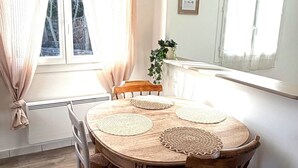 Ruokailutila, jossa on pyöreä pöytä, neljä tuolia ja ruukkukasvi.