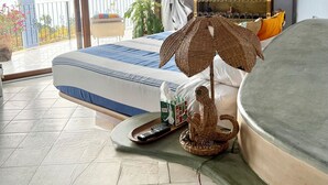 Et soveværelse med seng, loftventilator, balkon med udsigt og en pyntelig hylde.