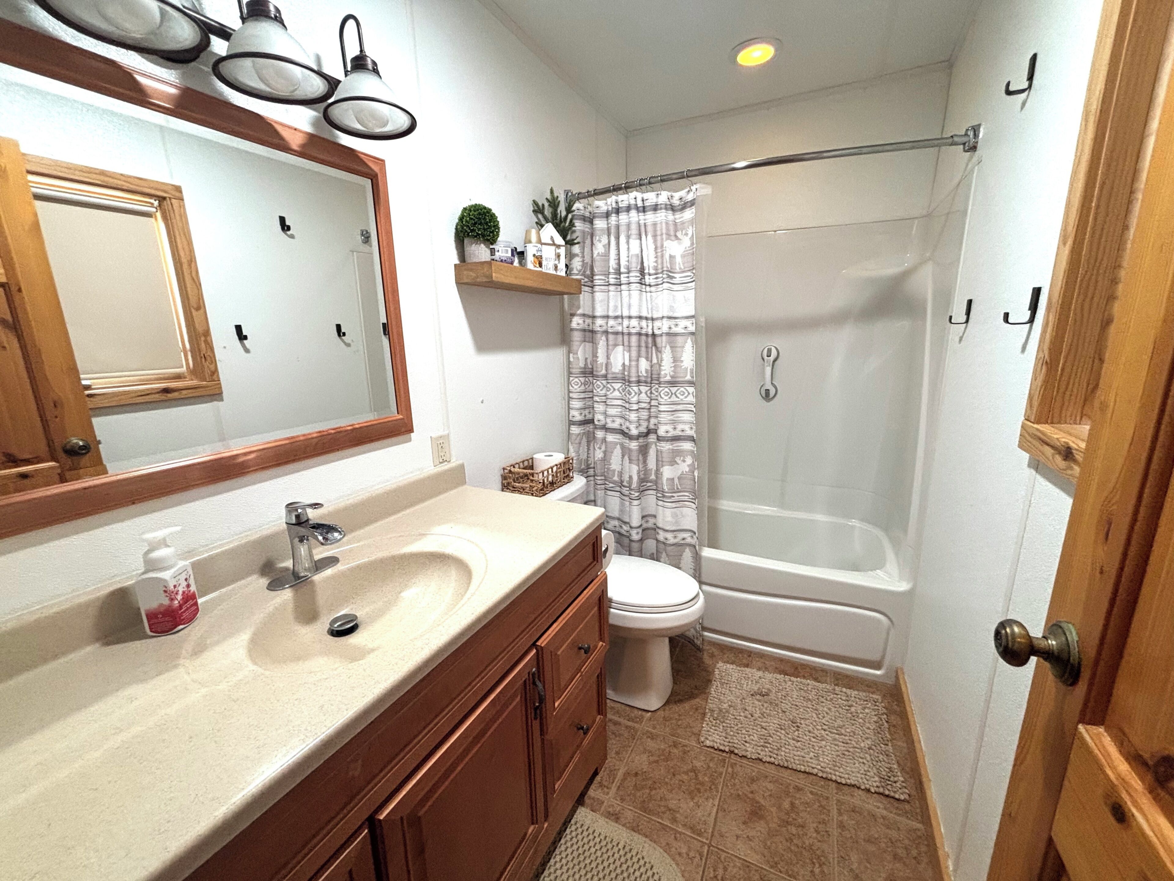 Une salle de bain équipée d’un lavabo, d’un miroir, de toilettes et d’une douche.