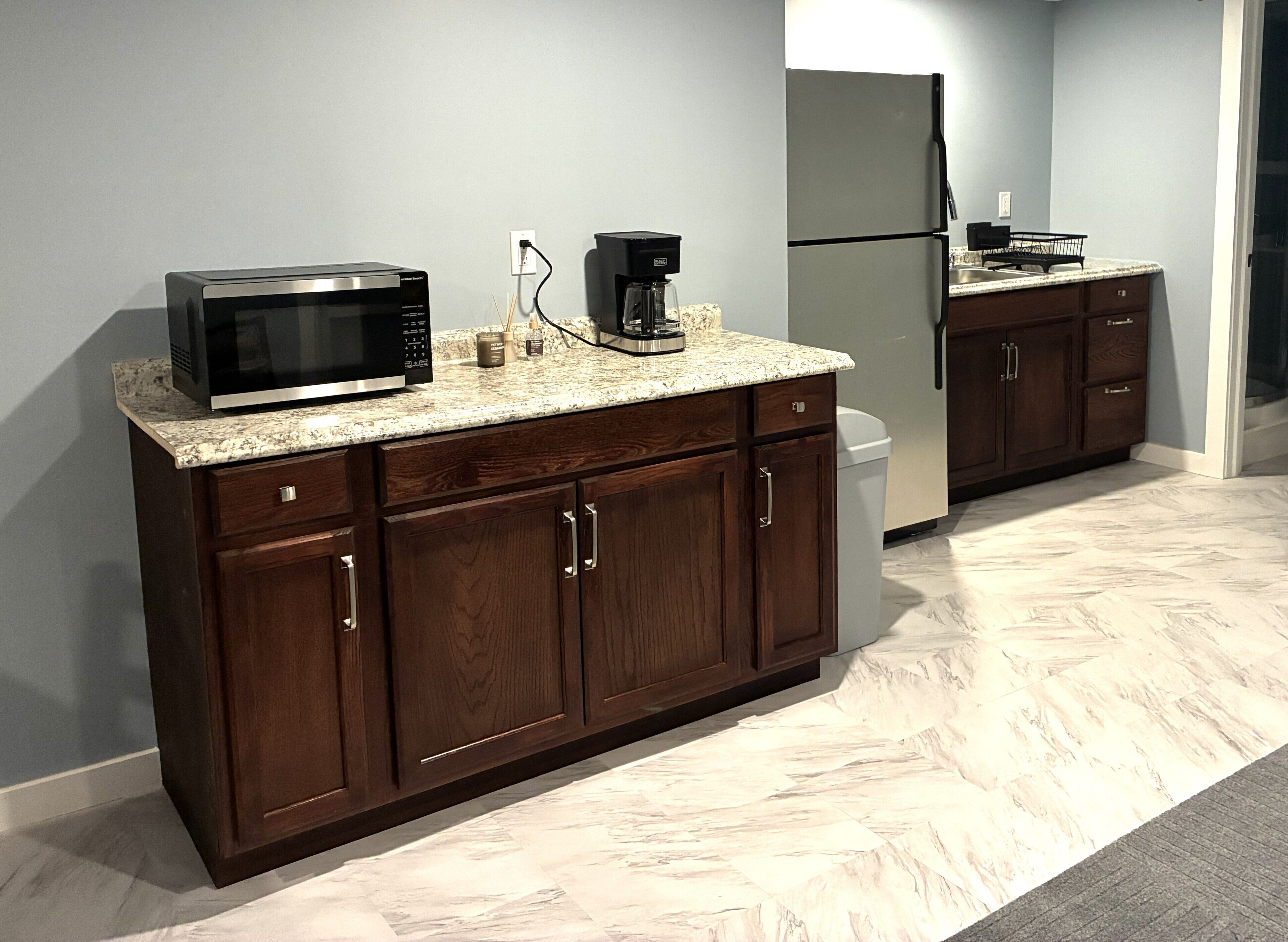 A kitchen with a microwave, coffee maker, and refrigerator.