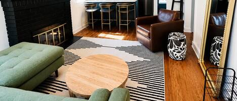 Un salon moderne avec une cheminée, un canapé, une table basse et une cuisine en arrière-plan.