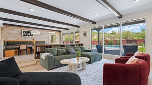 Amplia sala de estar con un sofá, un sillón rojo, una mesa de centro y un comedor con banco y mesa.