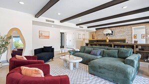 Un amplio salón con un sofá rojo, un sofá verde y una mesa de centro blanca.