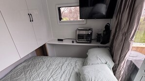 Une chambre compacte comprenant un lit, une télévision, un four à micro-ondes et une petite kitchenette.