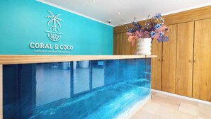 Un espace d’accueil avec un mur de couleur turquoise, un meuble en bois et un grand aquarium.
